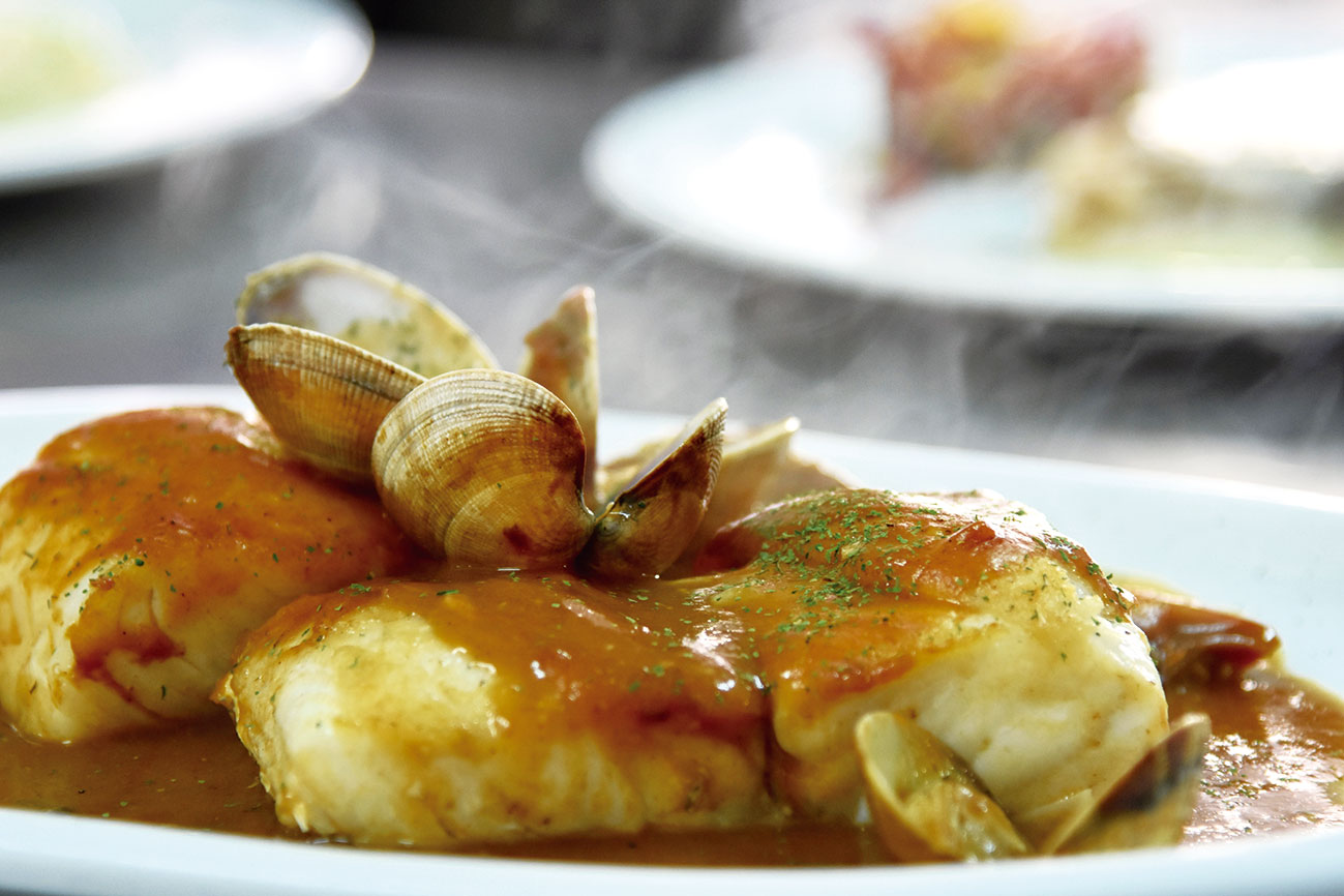 Plato humeante de pescado con almejas a disfrutar en la Cafetería del Camping Las Hortensias